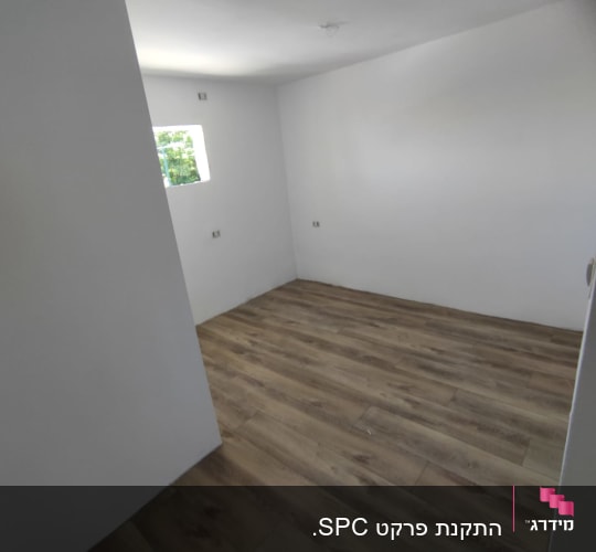 רצפת פרקט עץ בחדר ריק עם קירות לבנים